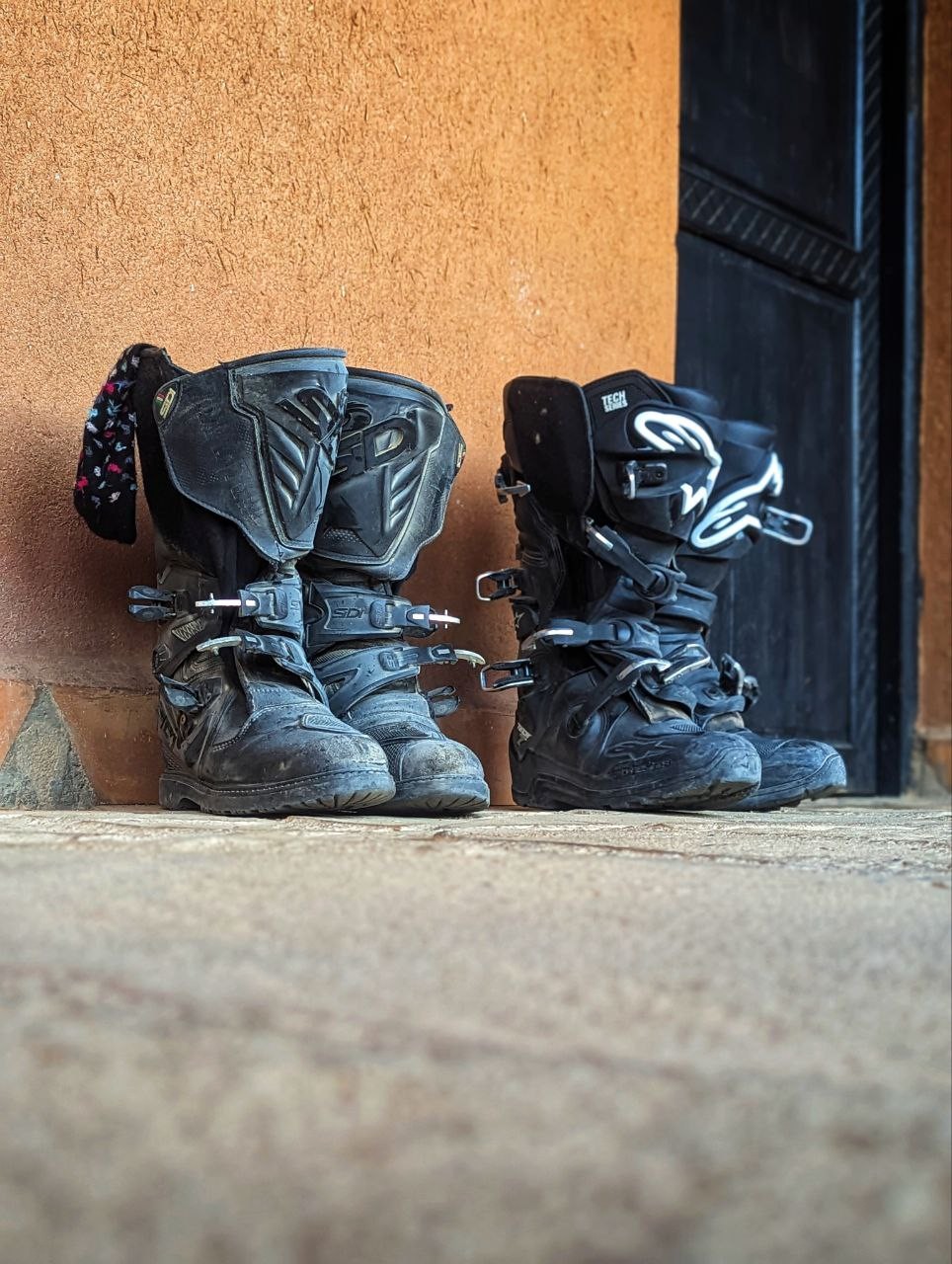 A pair of dusty motorcycle boots left outside the door of a hotel room