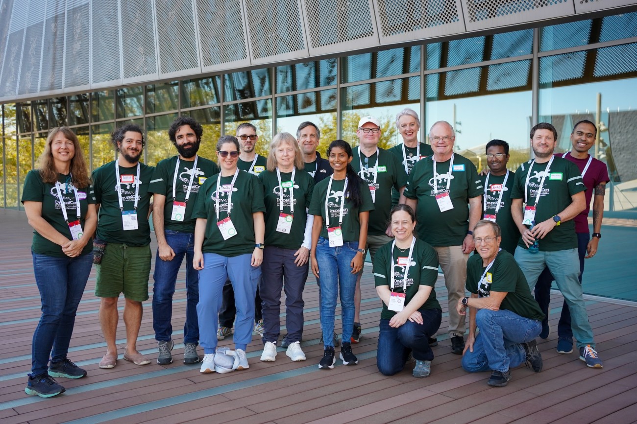 The team of mentors outside the building at DrupalCon Europe, all wearing green mentor t-shirts