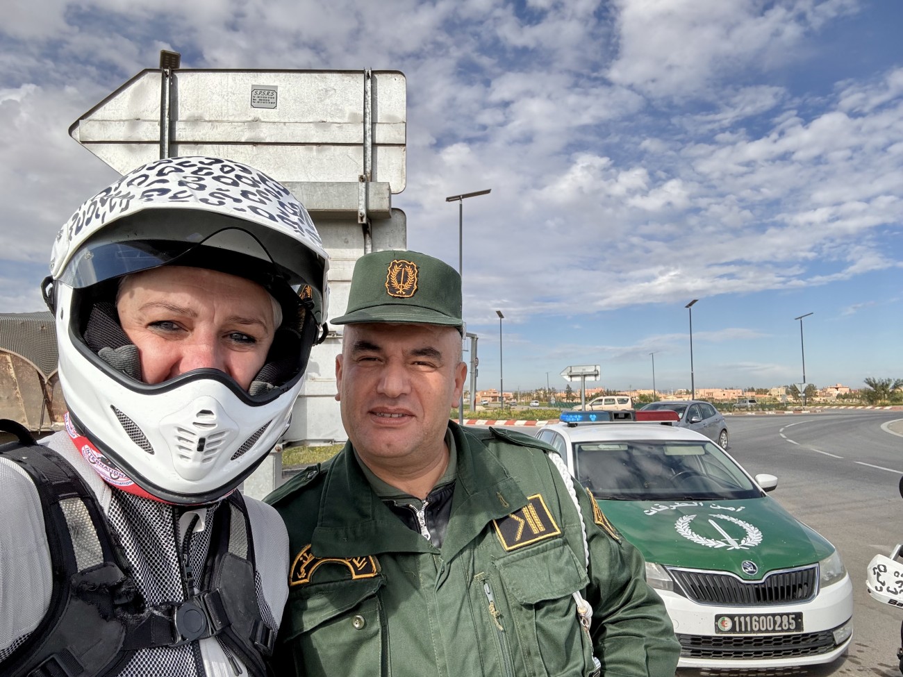 Selfie of myself, wearing a motorbike helmet, and an Algerian police officer