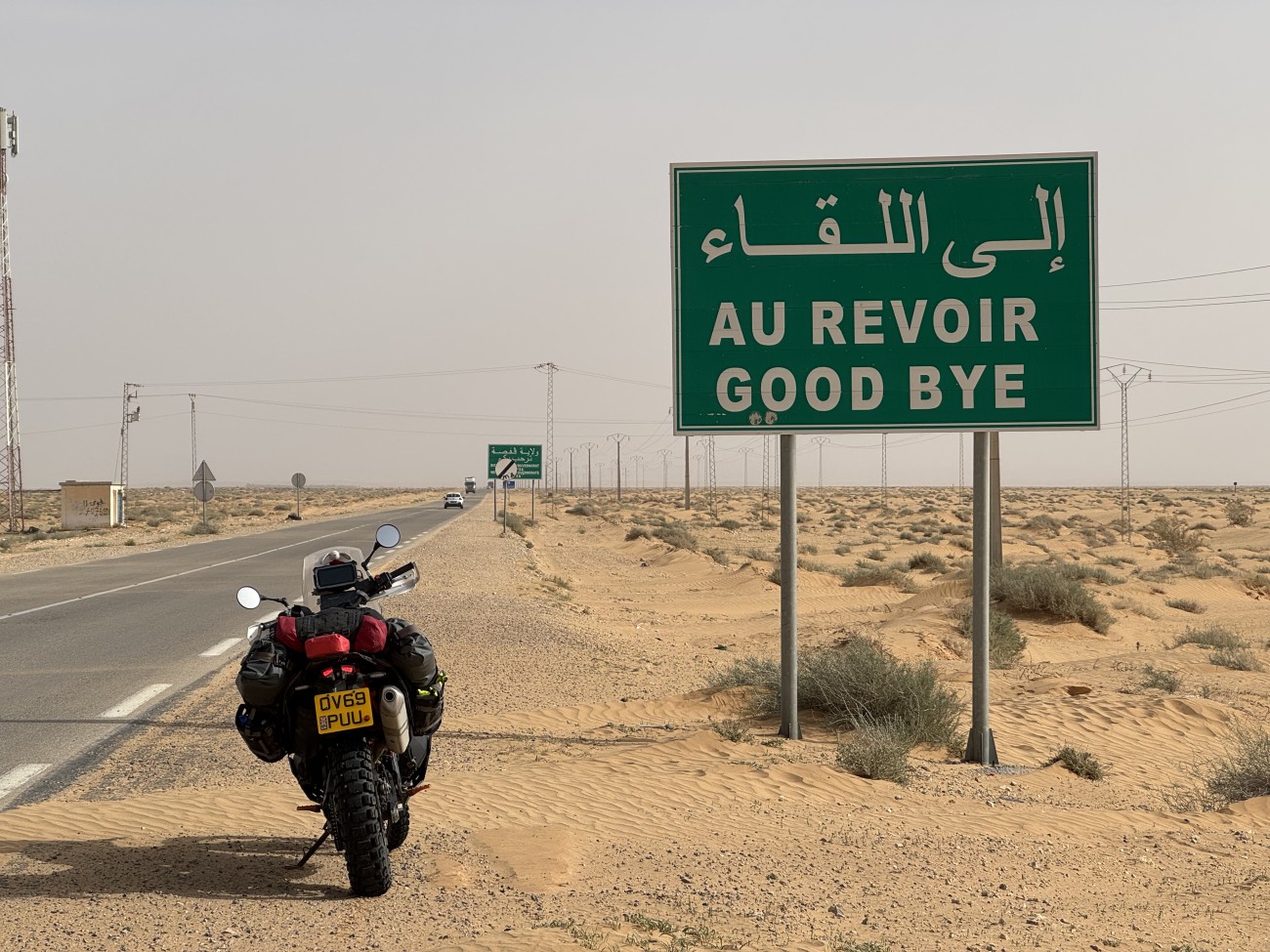 My bike parked next to a road sign saying Au Revoir Good Bye