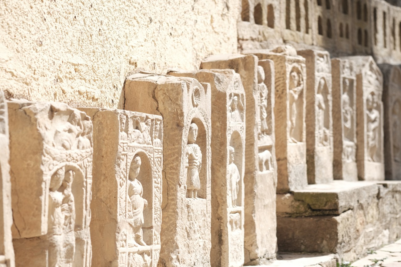 A series of stone blocks, a little like gravestones, each with a carving of little people in them