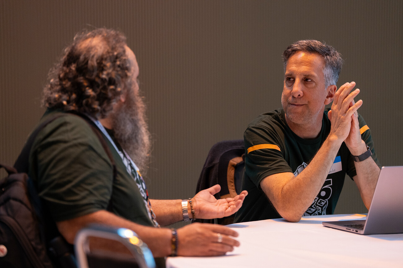 Two people, one in a green mentor t-shirt, discussing an issue they are working on